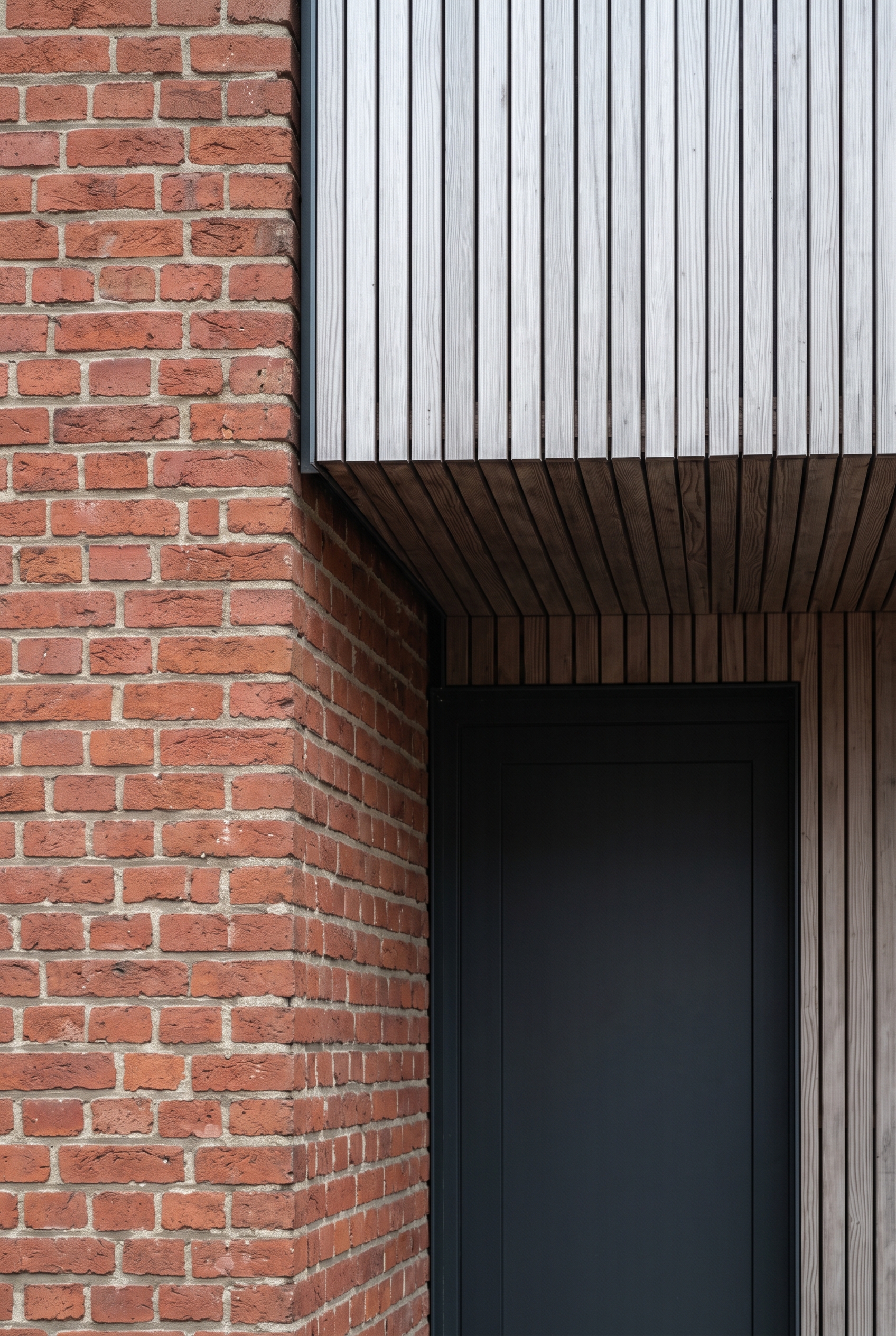Angle rentrant de façade, extension en ossature bois portée au-dessus d'une porte d'entrée, lecture domogenie du bâti